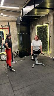 Bir spor salonunda ters mekik aletinde  orta yaşlarda, spor giyimli bir kadın (Sevgi Mart Göcen) yan tarafında elleri belinde duran spor giyimli bir kadınla (Spor hocası Ceyda Barut)  karşılıklı gülümsüyorlar.