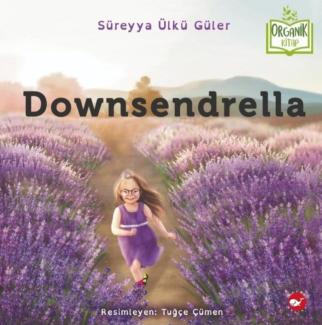 Downsendrella isimli kitap kapağı. Sağlı sollu sıralanmış lavanta çiçekleri arasında gülerek koşan lila rengi elbiseli, beyaz kemerli, sarı uzun saçlı, gözlüklü, down sendromlu bir kız çizimi. Arka planda dağlar ve ağaçlar var. En üstte ortada Süreyya Ülkü Güler ve onun sağ tarafından açık bir kitap çizimi içinde Organik Kitap yazıyor. Altta ortada Resimleyen Tuğçe Çümen yazıyor. Sağda çok küçük kırmızı bir dairenin içinde bir balina çizimi bulunuyor.