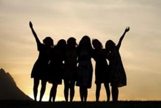 Gün batımına karşı yan yana ayakta duran ve birbirlerine kollarını dolamış altı kadın silueti. Sol ve sağ baştaki iki kadın bir kollarını havaya doğru kaldırmış.