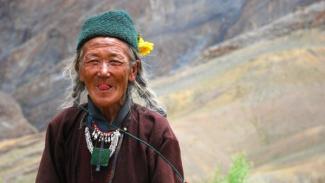 Kayalık bir dağda Tibetli bir adam dil çıkararak gülümsüyor. Beyaz saçlı adamın saçları iki yandan örülmüş şekilde sırtına doğru uzanıyor. Kafasında yeşil renkli, takkeye benzeyen yöresel bir şapka, şapkanın sağ tarafında sarı renkli canlı bir çiçek iliştirilmiş. Üzerinde yöresel giysi bulunan adamın kırışık derili yüzü oldukça bronzlaşmış. Adam gözleri kısık bir halde gülümseyerek dil çıkarıyor.