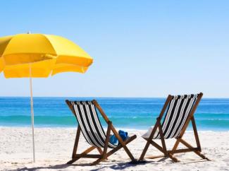 Mavi bir deniz ve kumlu bir plaj. Plajda, sol tarafta açık sarı renkte büyük bir plaj şemsiyesi yer alıyor. Şemsiyenin hemen sağında, siyah beyaz çizgili iki adet ahşap şezlong birbirine yakın duruyor. Sol şezlongun üzerinde mavi renkli bir havlu veya giysi duruyor. Sağdaki şezlongun ise oturma yerinde beyaz bir şapka bulunuyor. Şezlongların hemen arkasında, ufuk çizgisine kadar uzanan pırıl pırıl, turkuaz renkte sakin bir deniz görünüyor. Gökyüzü ise bulutsuz, açık mavi renkte.